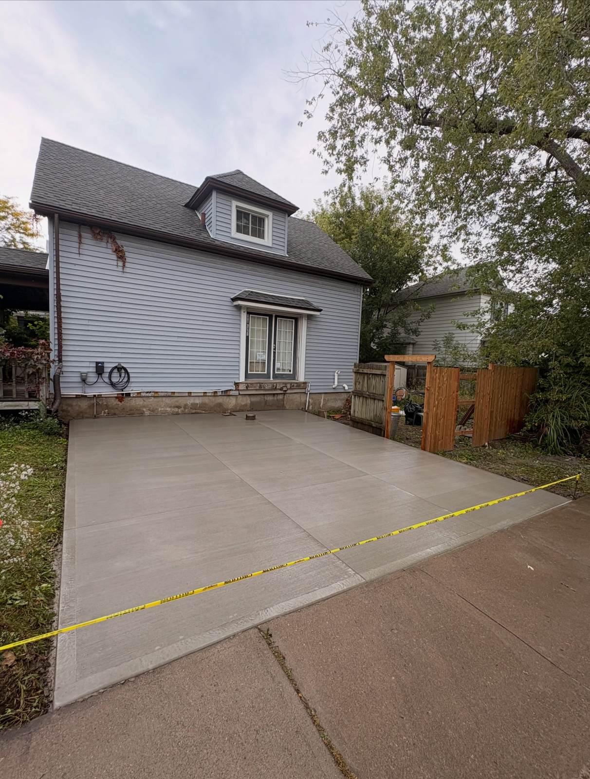Broom-finish concrete driveway of about 470 square feet beside a blue-sided house